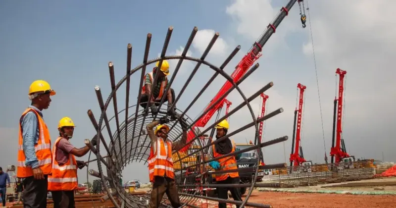 Construction crew building rebar cage with cranes